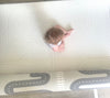 Baby sitting on a padded playmat. Playmat shows two sided design with track side of the playmat visible.