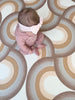 Baby girl sitting on Archie Retro Large playmat. Side A of the playmat has a brown arch playmat.
