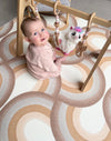 Baby girl playing with a wooden gym, while sitting on Archie Retro Large playmat.