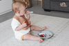 Baby eating a snack on the padded Baby Driver Boho playmat. Side A has a neutral boho design.