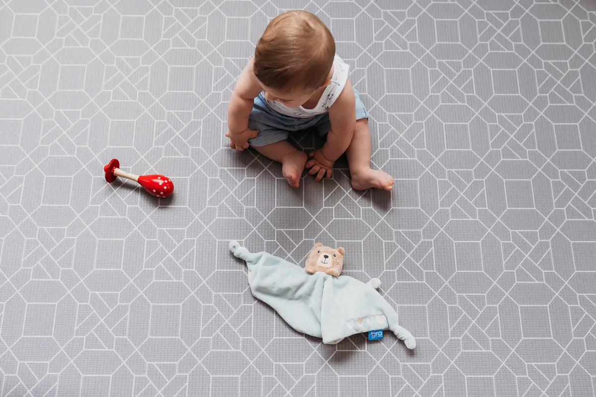 Kid playing on My name is Earl playmat. Side A grey geometric pattern.
