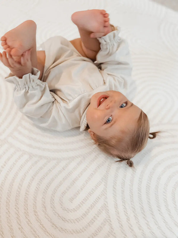 Baby on an Archie Baby Driver playmat. Playmat has arches on one side.