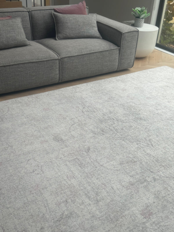 Light gray rug with a distressed texture, placed in a room with a gray ...