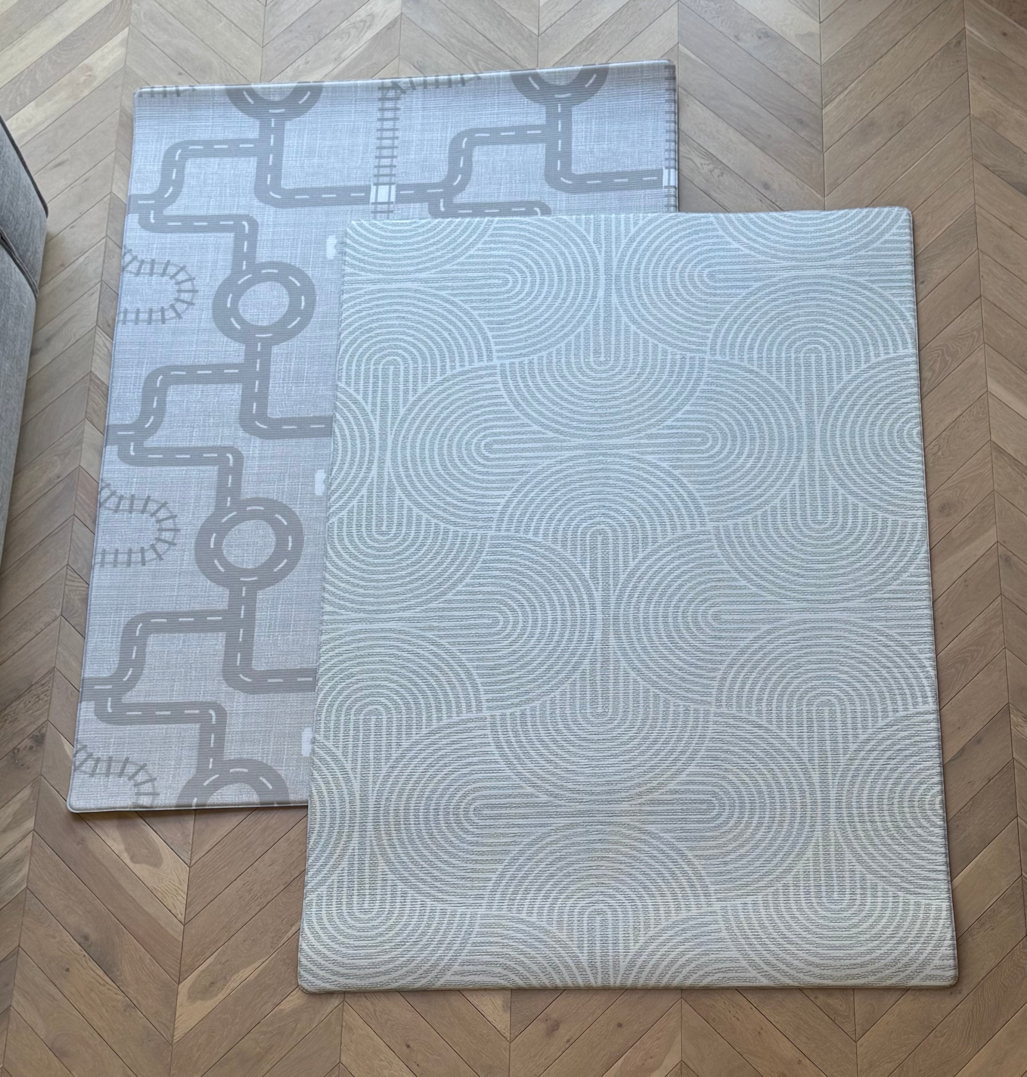 Two patterned rugs on a wooden floor, featuring a grey design that complements the natural wood tones.
