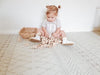 Girl playing with wooden blocks on the Baby Driver Boho playmat. Side A has a neutral boho pattern.