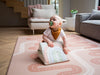 Baby with a tummy time toy on the Baby Driver Dusty Rose Boho playmat. Side B has a car track design.