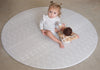 Baby sitting on Baby Driver Grey Boho round playmat. Side A has a neutral boho pattern.