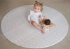 Baby sitting on Baby Driver Grey Boho round playmat. Side A has a neutral boho pattern.