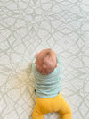 Baby doing tummy time on Baby Driver Trina playmat. Side A has a sage geometric pattern.