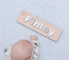 Baby with name sign on Forrest Baby Blue playmat. Side A has a blue geometric pattern.