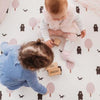 Kids playing on Forrest Blush large playmat. Side B has a tree and bear pattern. 