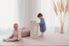 Kids playing on Forrest Blush large playmat. Side A has a pink geometric pattern.