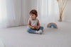 Kid sitting on Forrest Grey playmat. Side A has a grey geometric pattern.