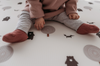 Kid sitting on Forrest Grey playmat. Side B has a tree and bear pattern. 