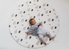 Kid laying on Forrest Grey Round playmat. Side B has a tree and bear pattern. 