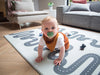 Kid playing on Sage Archie Baby Driver playmat. Side B has a car track design.